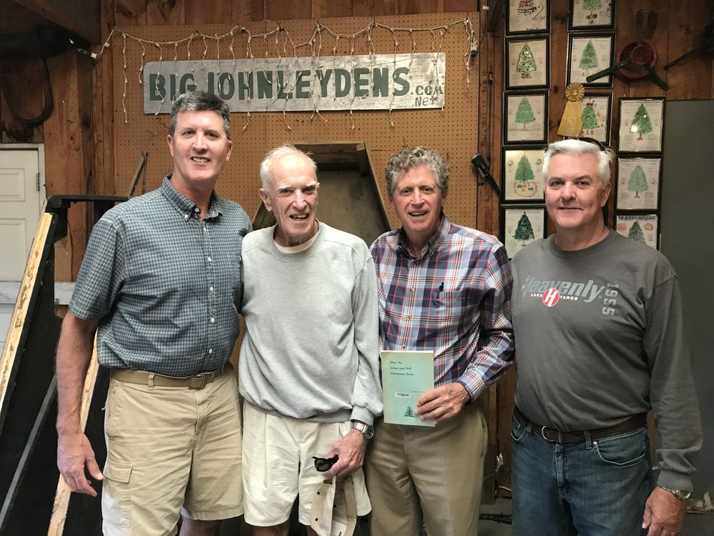 Four men standing under the Big John Leydens sign